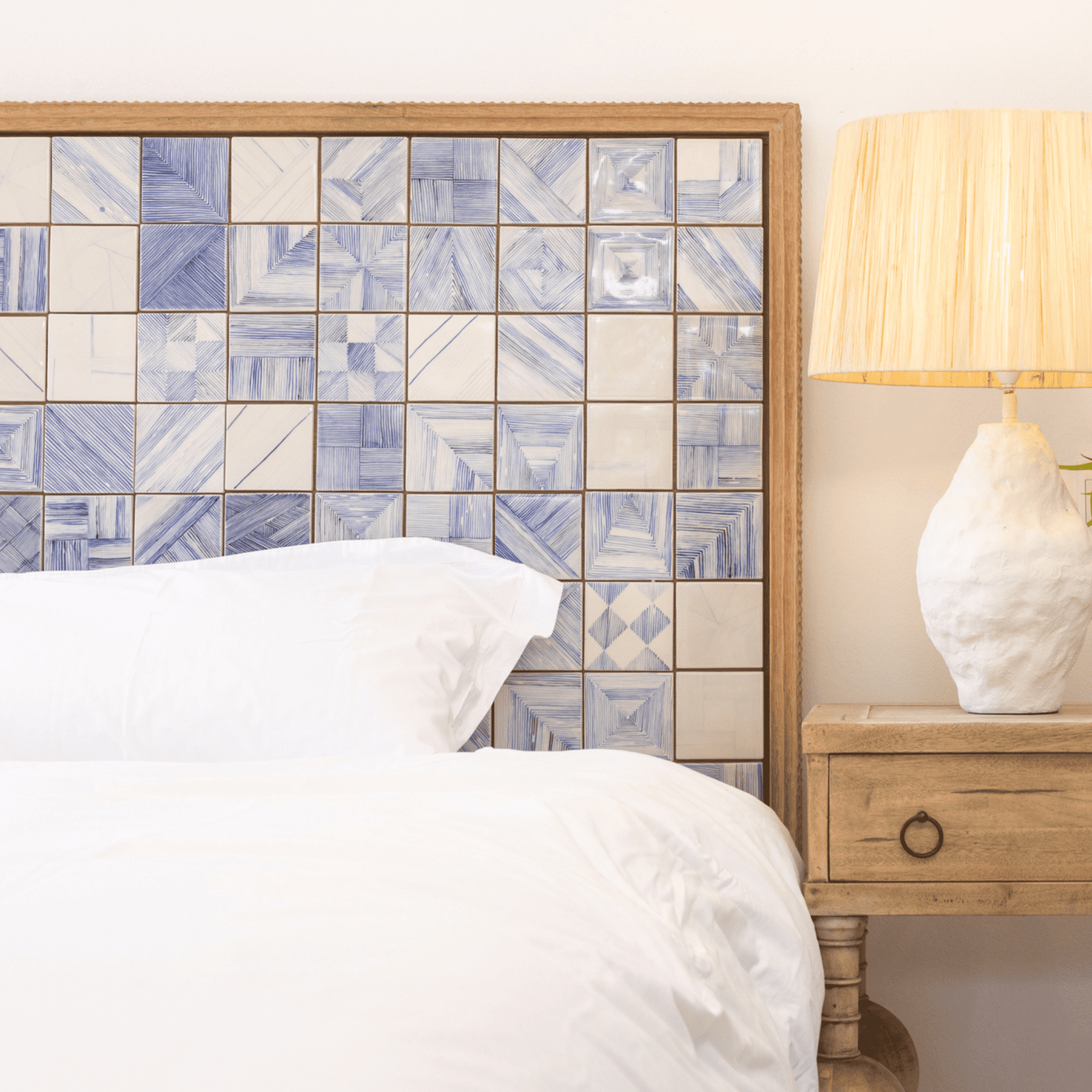 White bed with blue tiled headboard and lamp