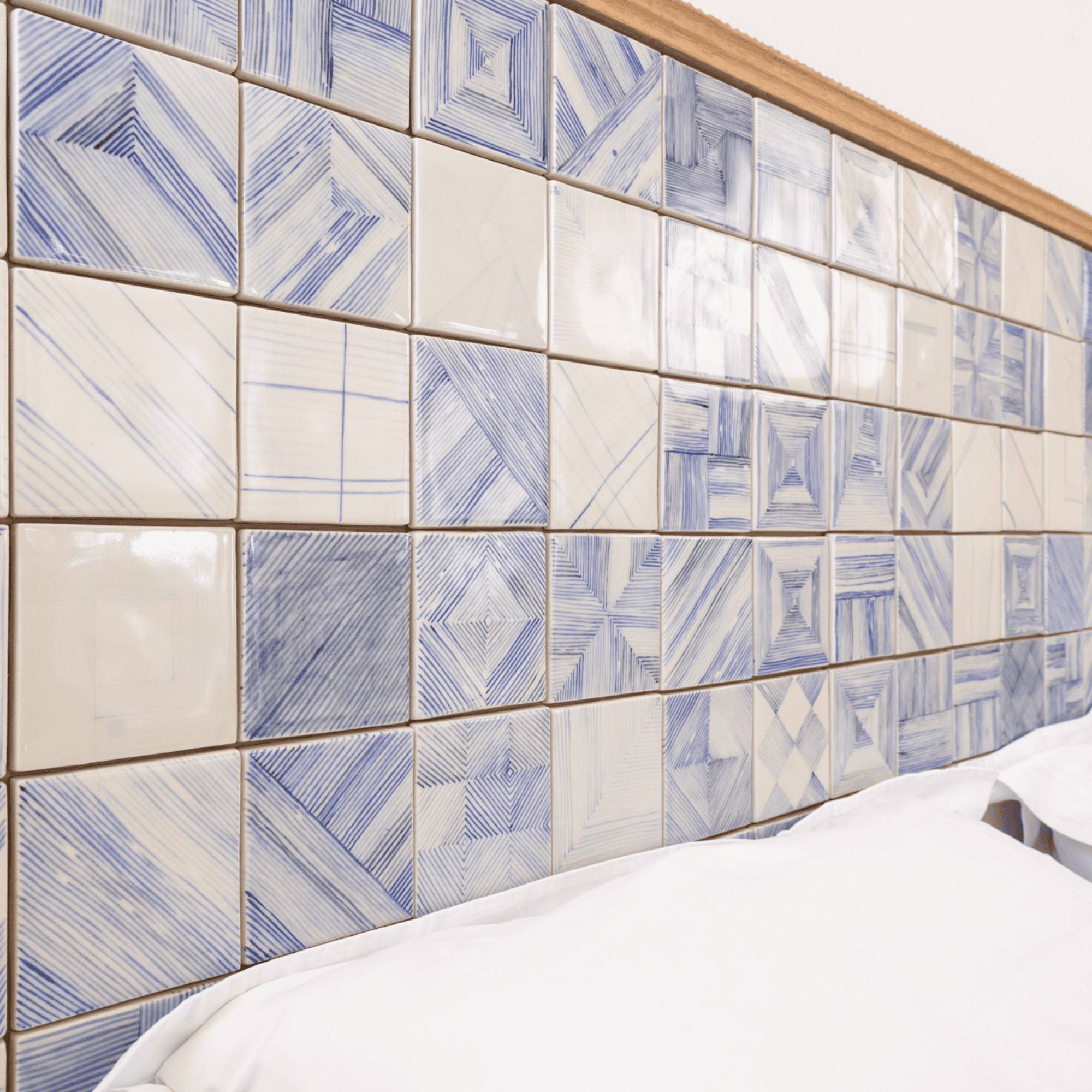Blue patterned tile headboard with white pillows