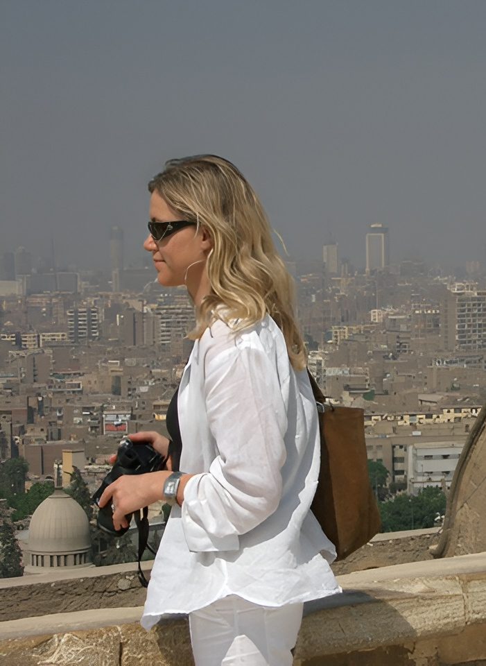 Woman in white holding camera overlooking city